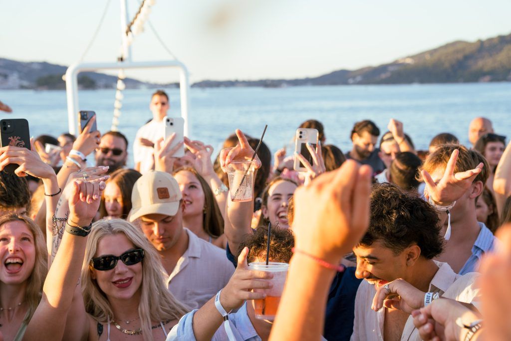 Oasis Boat Party Skiathos sunset crowd celebrating on deck with drinks