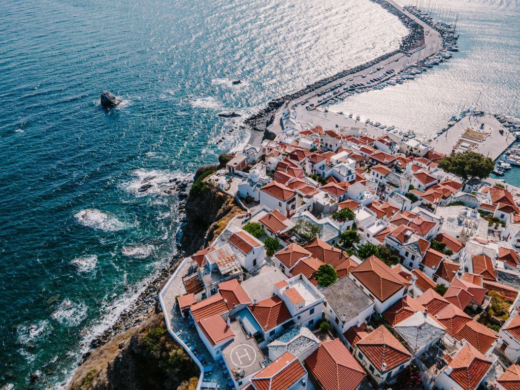 Aerial view of Skopelos Town in the Sporades Islands, Greece, showing red-roofed houses by the sea and the main harbor.
