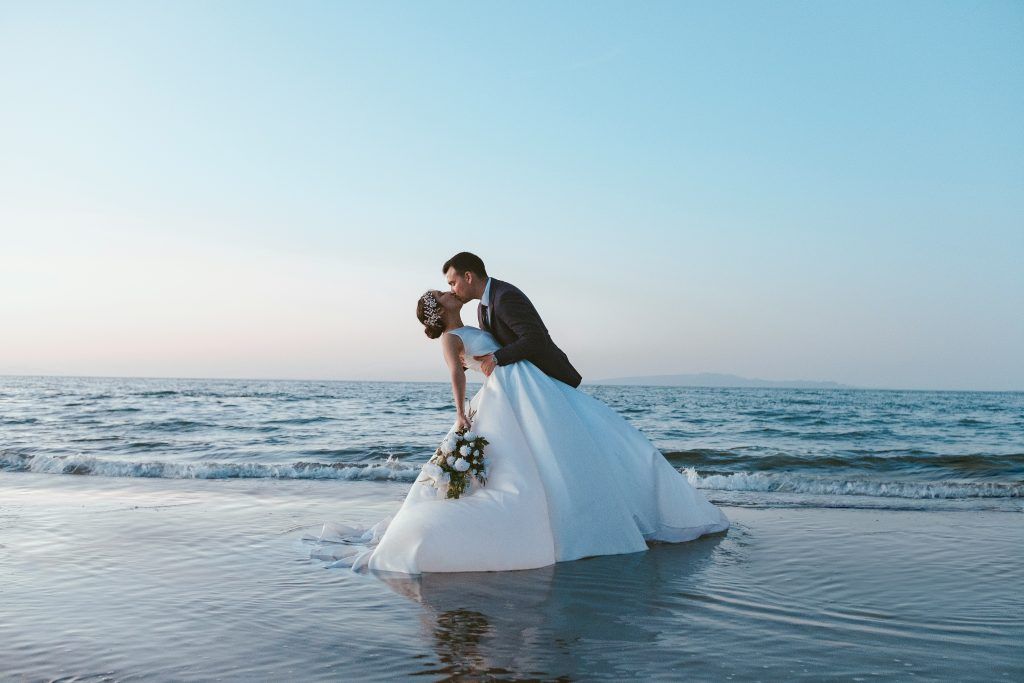 Wedding planner organizing a romantic destination wedding in Skiathos with couple embracing by the sea.