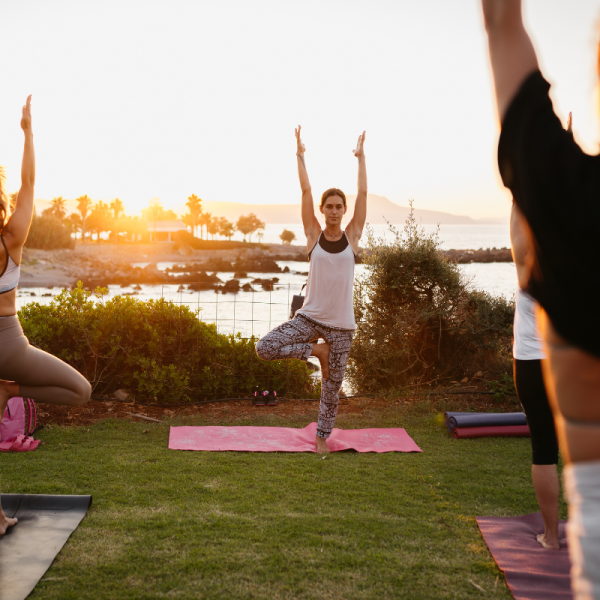 Yoga instructor leading an outdoor yoga class in Skiathos during sunset with relaxing island scenery.