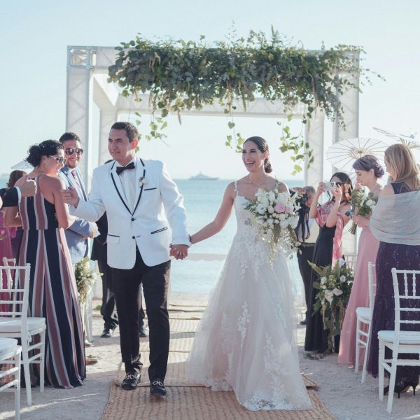 Destination wedding in Skiathos with happy couple walking down the aisle during a beach ceremony planned by local wedding planner.